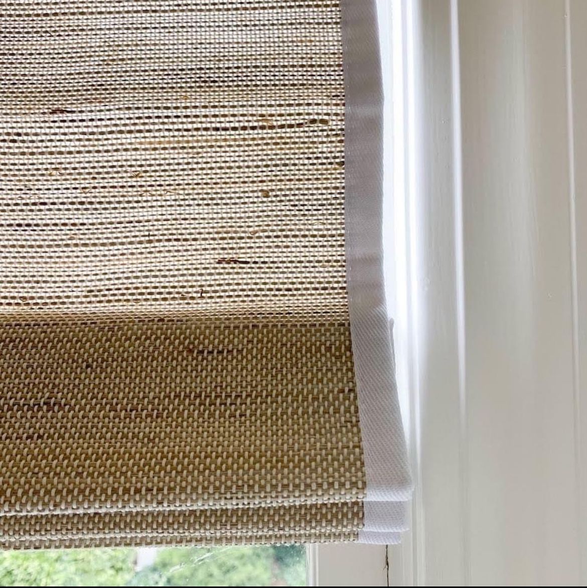 A close up of a roman shade on a window.