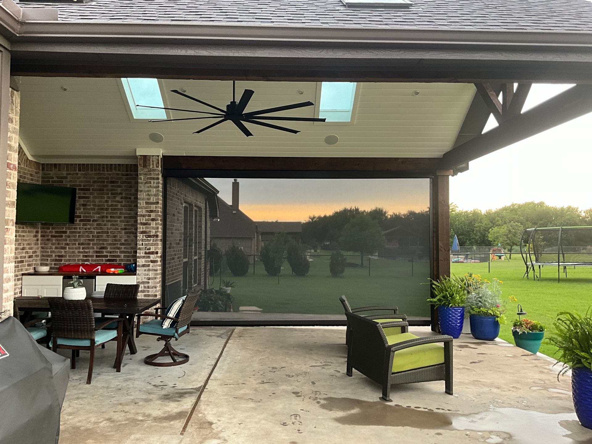 A patio with a table and chairs and a ceiling fan.