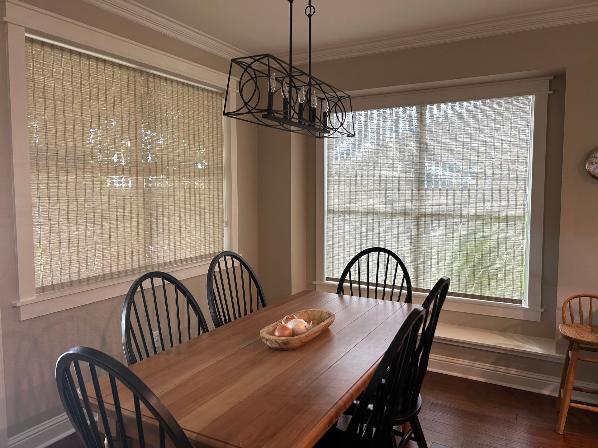 A dining room with a wooden table and chairs and a large window.