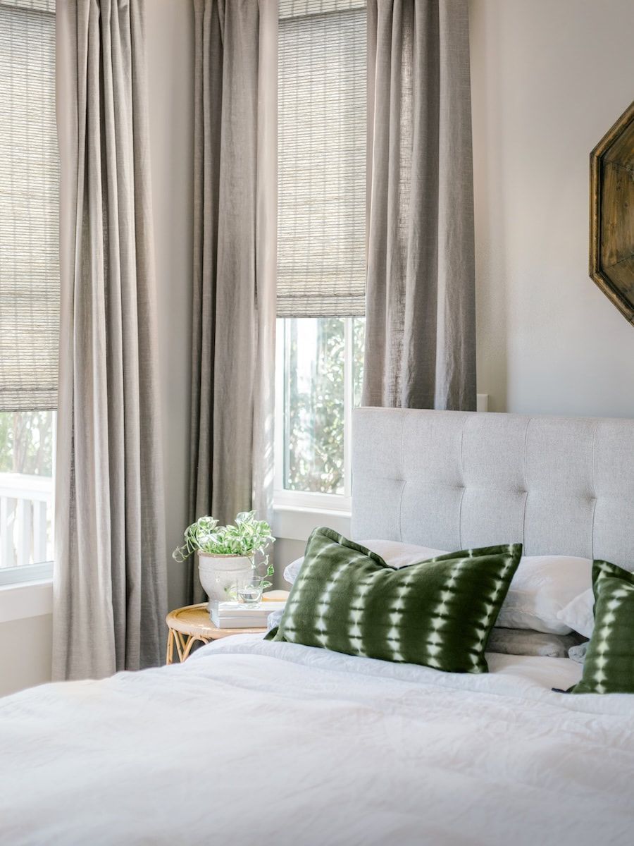 A bedroom with a bed , nightstand , and two windows.