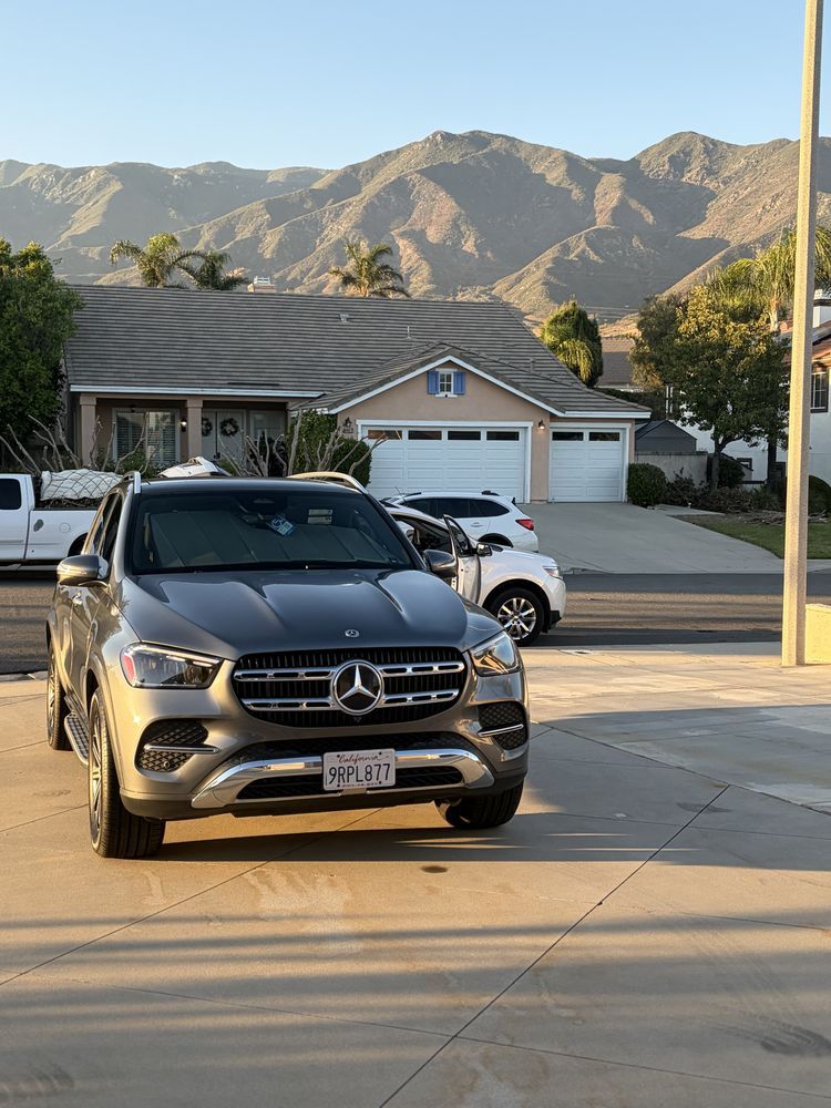 Gray Mercedes SUV parked in front of a house, with mountains in the background.