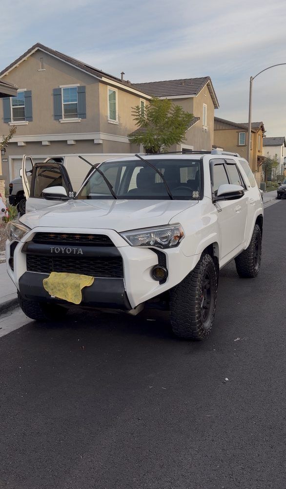 White Toyota 4Runner parked on a street in front of houses.