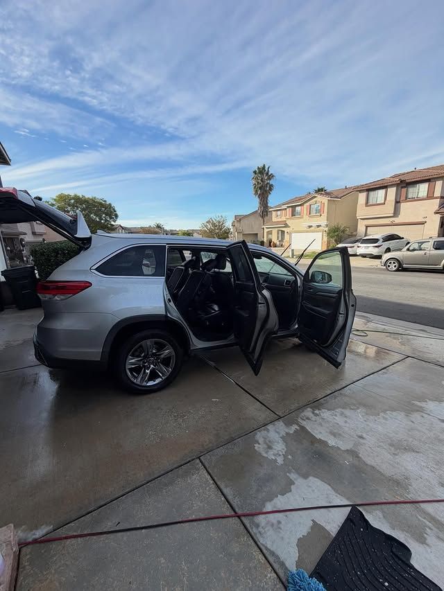 Silver SUV with open doors on a driveway under a cloudy blue sky.