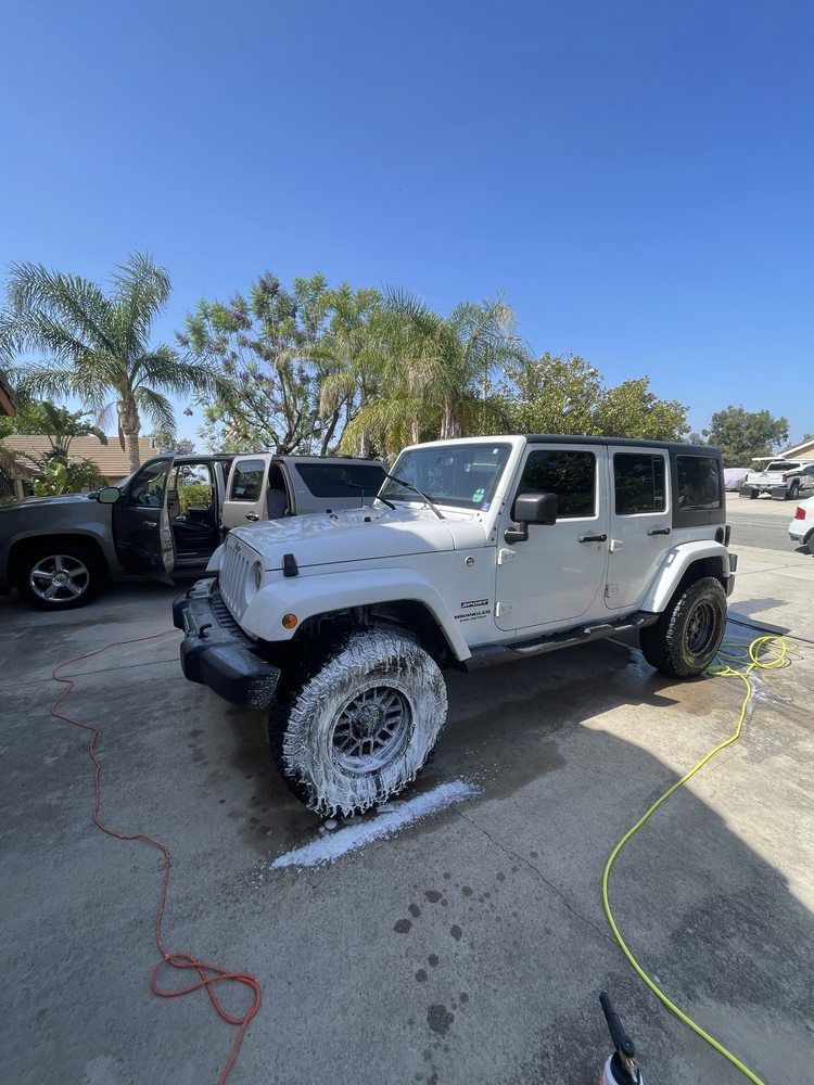 White Jeep Wrangler being washed outside on a sunny day.