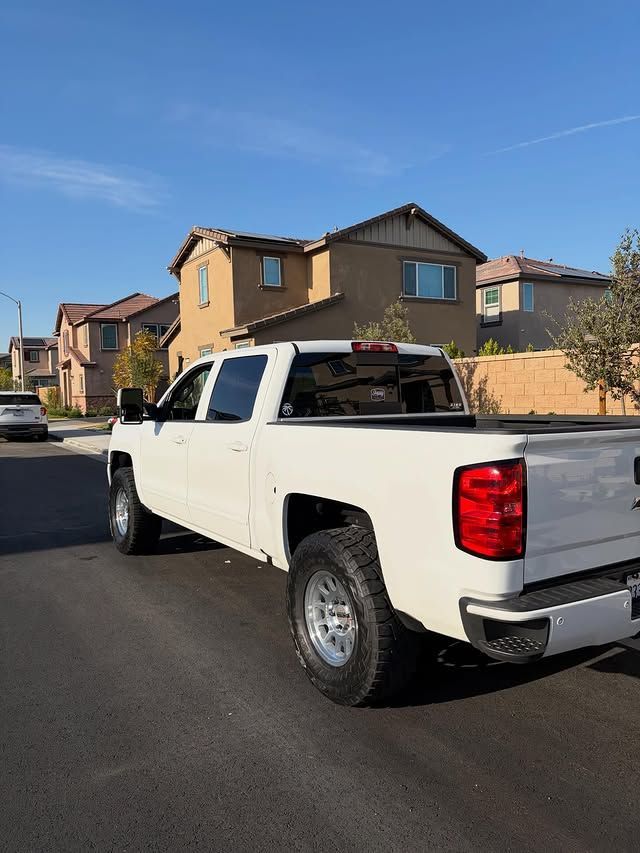 White pickup truck parked on street, residential setting with houses and blue sky.