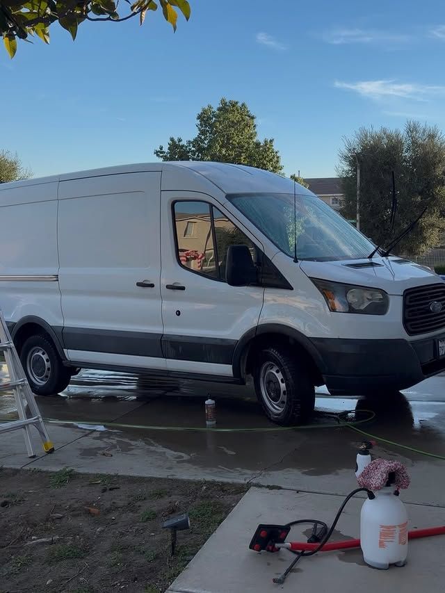 White cargo van being washed outside on a sunny day.