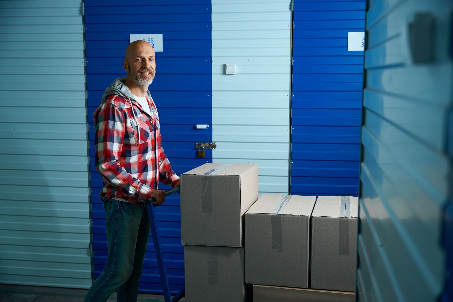 A man is pushing a pallet truck full of boxes in a warehouse.