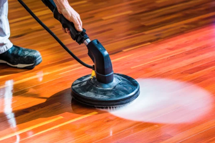 A person is cleaning a wooden floor with a machine.