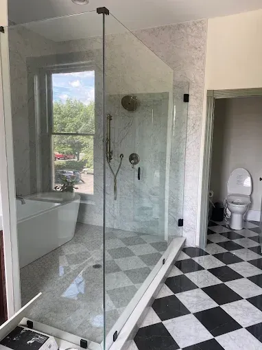 A modern bathroom featuring a glass shower, a freestanding white tub, and a black-and-white checkered floor.
