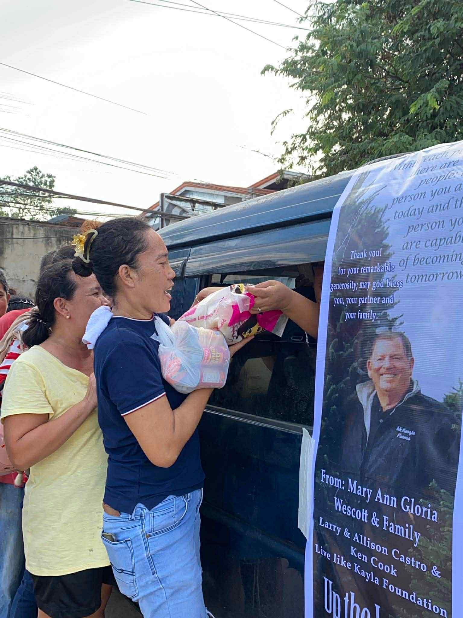 People giving food in a vehicle decorated with a memorial poster.