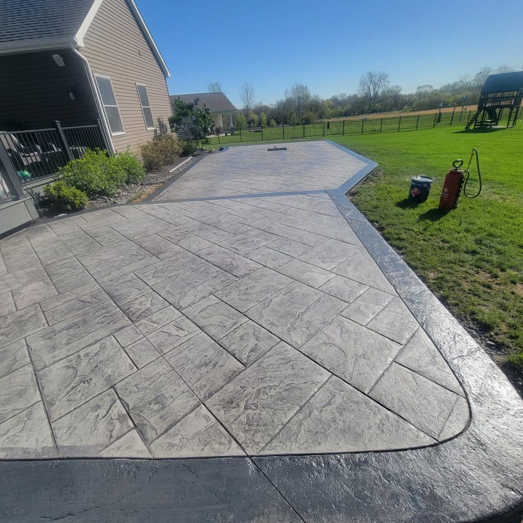 A concrete patio in front of a house with a fire hydrant in the grass