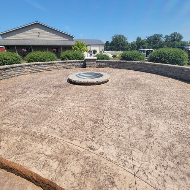A concrete patio with a fire pit in the middle