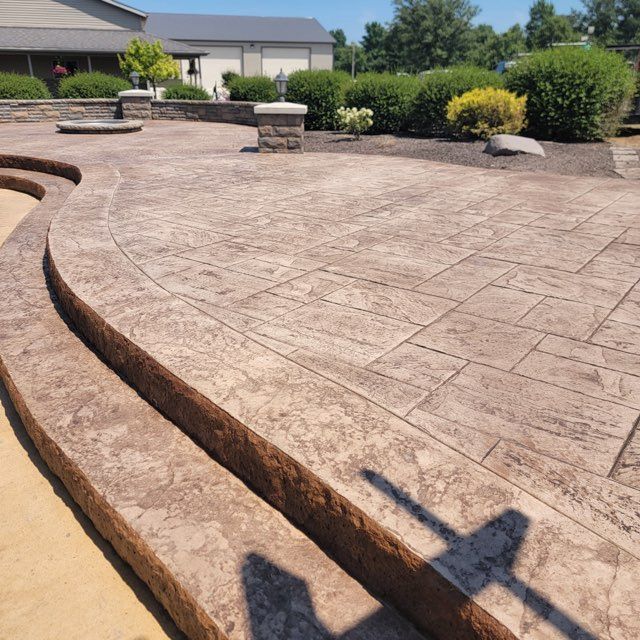 A concrete patio with steps and a house in the background