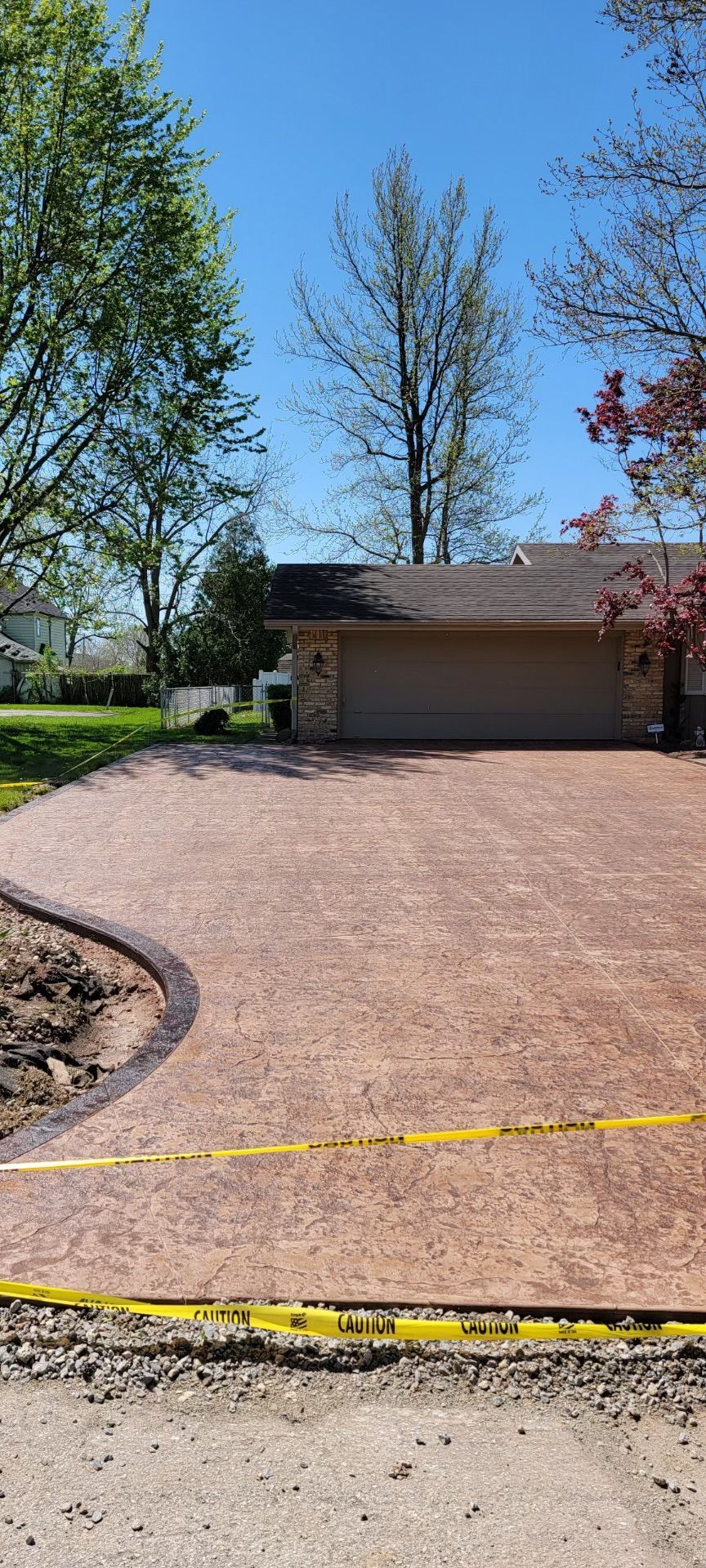 A driveway leading to a house with a garage and trees in the background