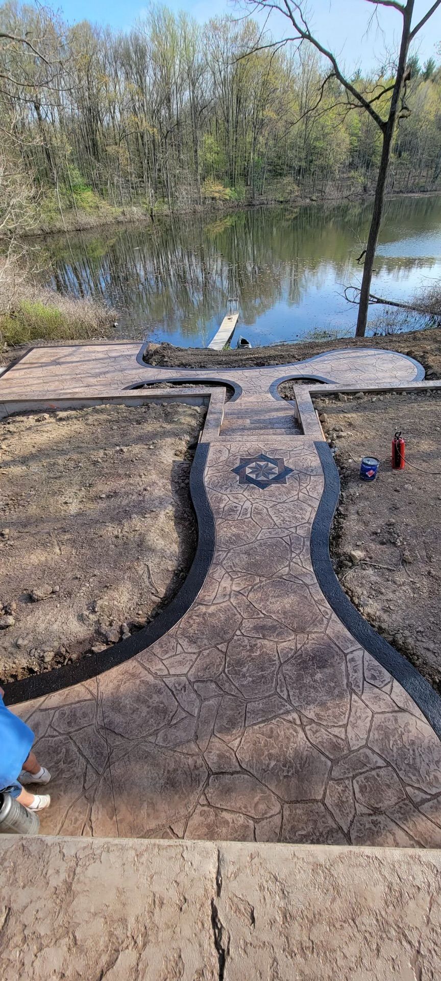 A concrete walkway leading to a lake with trees in the background