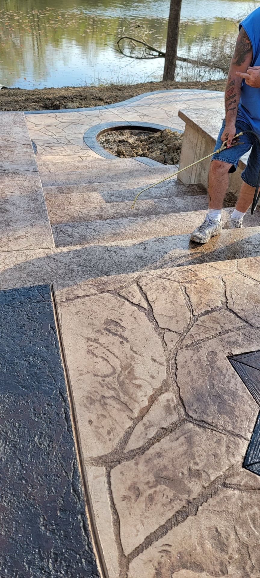 A man is cleaning a concrete patio with a hose