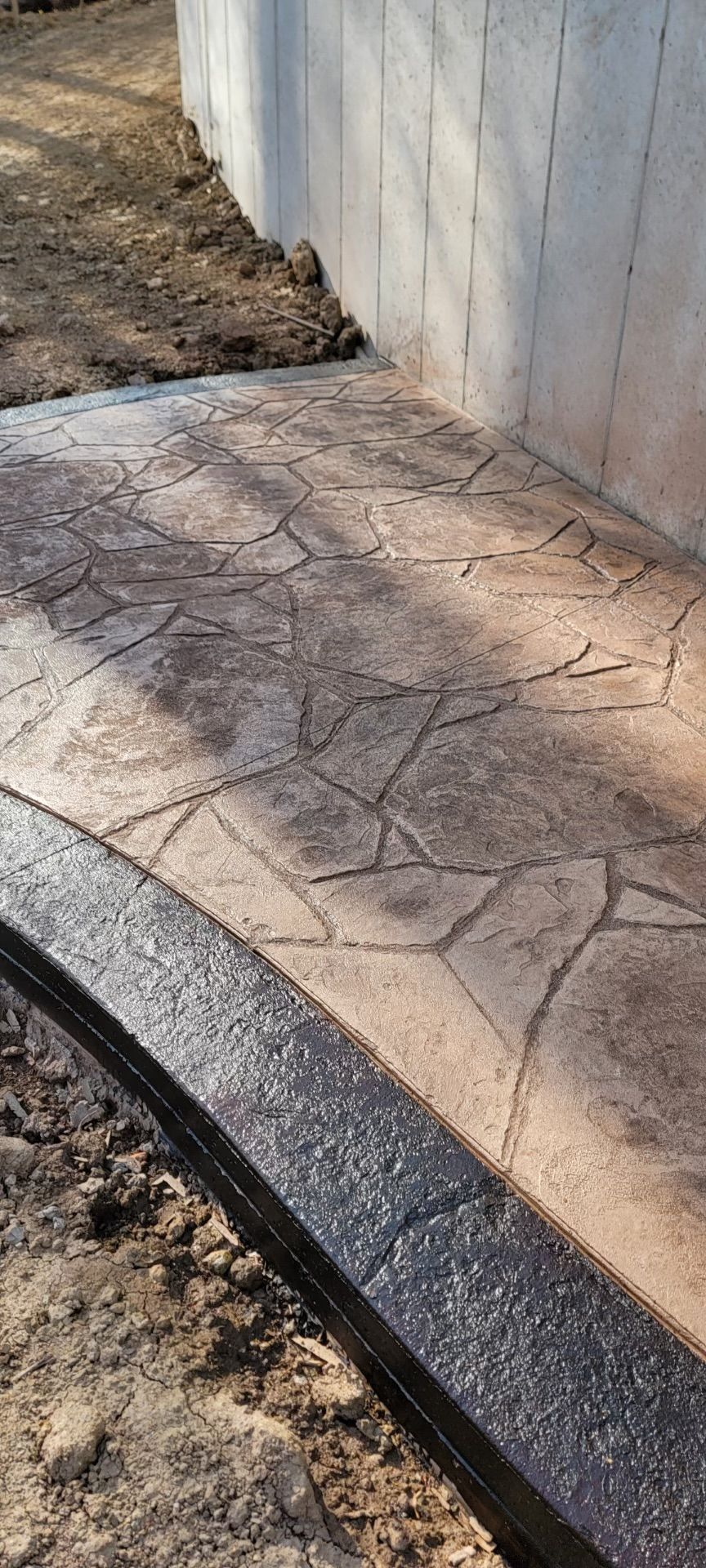 A concrete walkway is being built next to a concrete wall