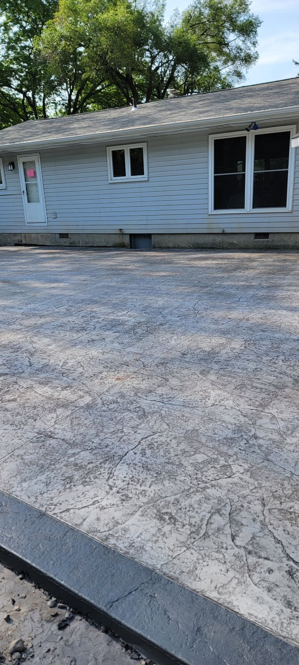 A house with white siding and a concrete driveway in front of it