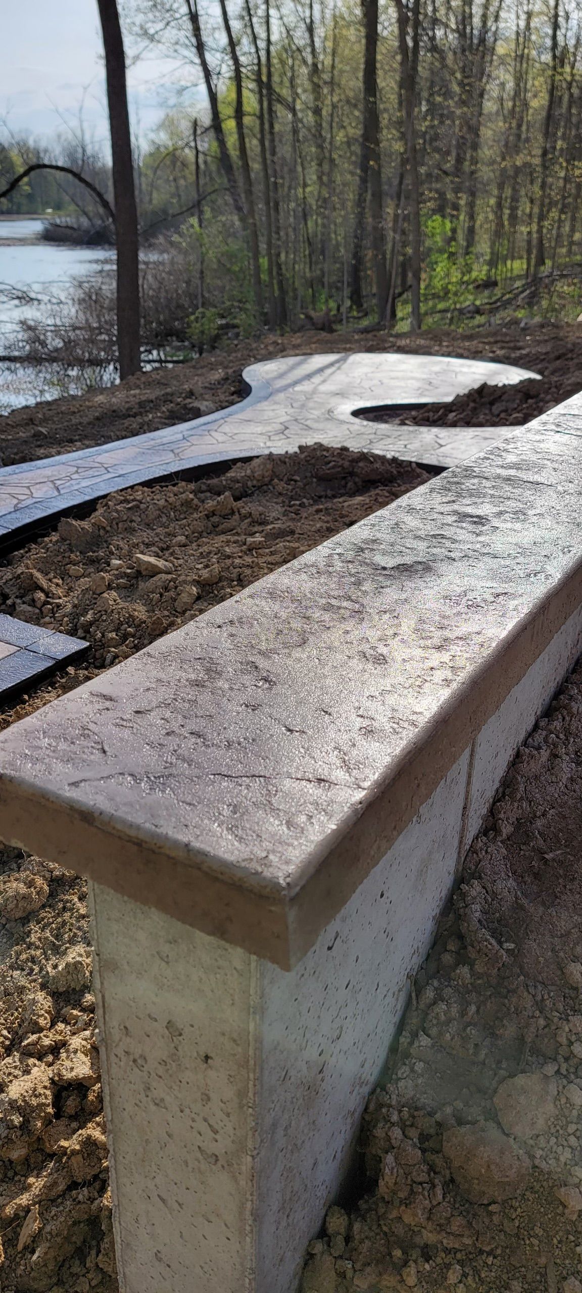 A concrete walkway leading to a lake with trees in the background