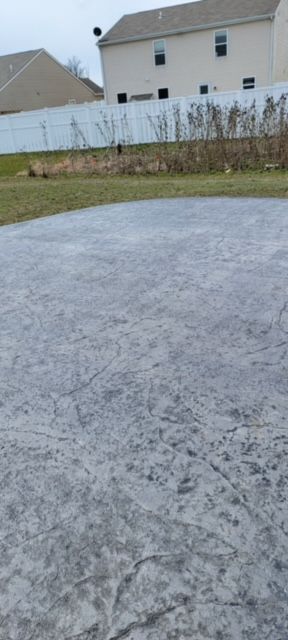 A concrete driveway with a white fence and a house in the background