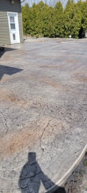 A shadow of a person is cast on a concrete driveway