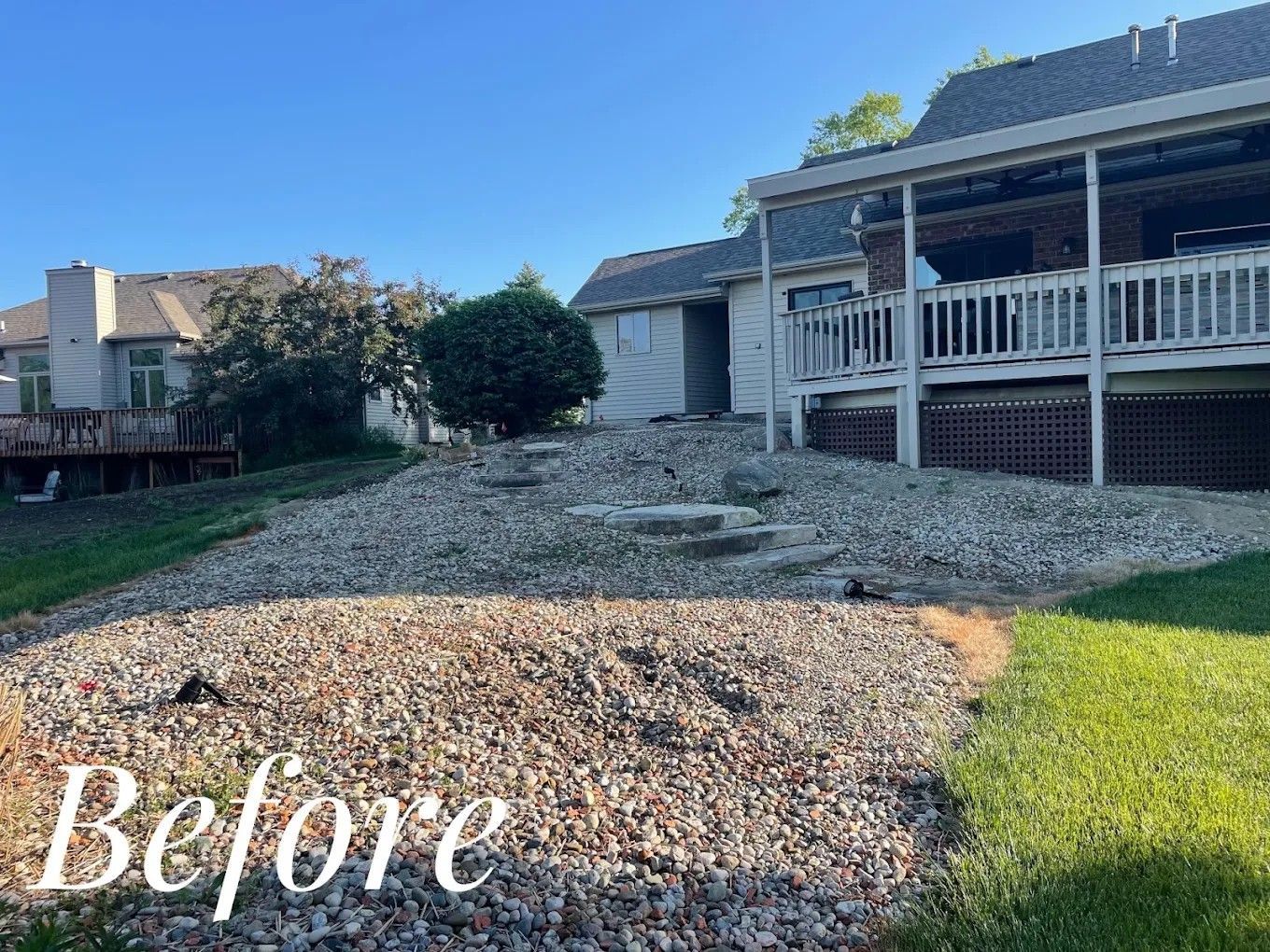 Backyard before photo with gravel path, green lawn, and house porch in the background