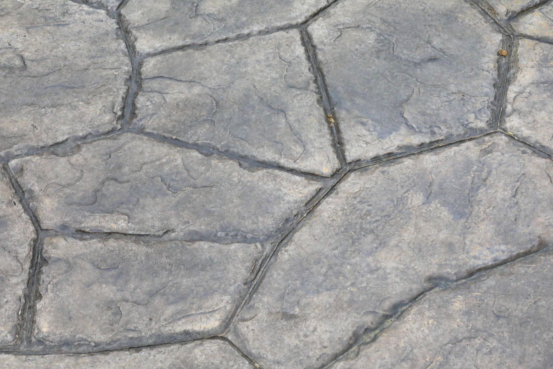 Close-up of a stamped concrete patio with a stone-like pattern and textured surface.