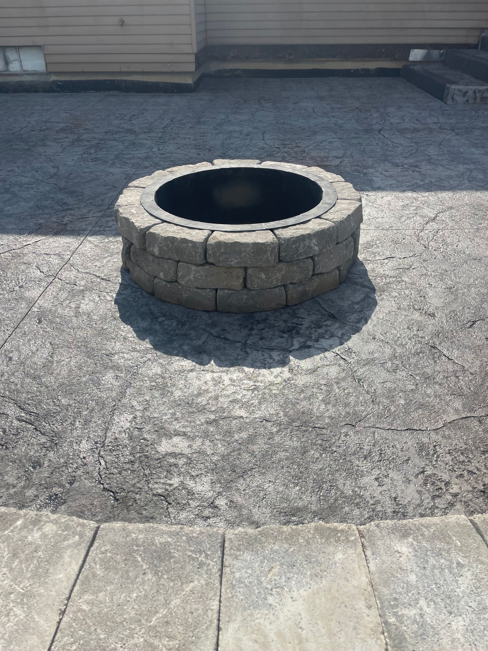 Fire pit made of stone blocks on a gravel patio.