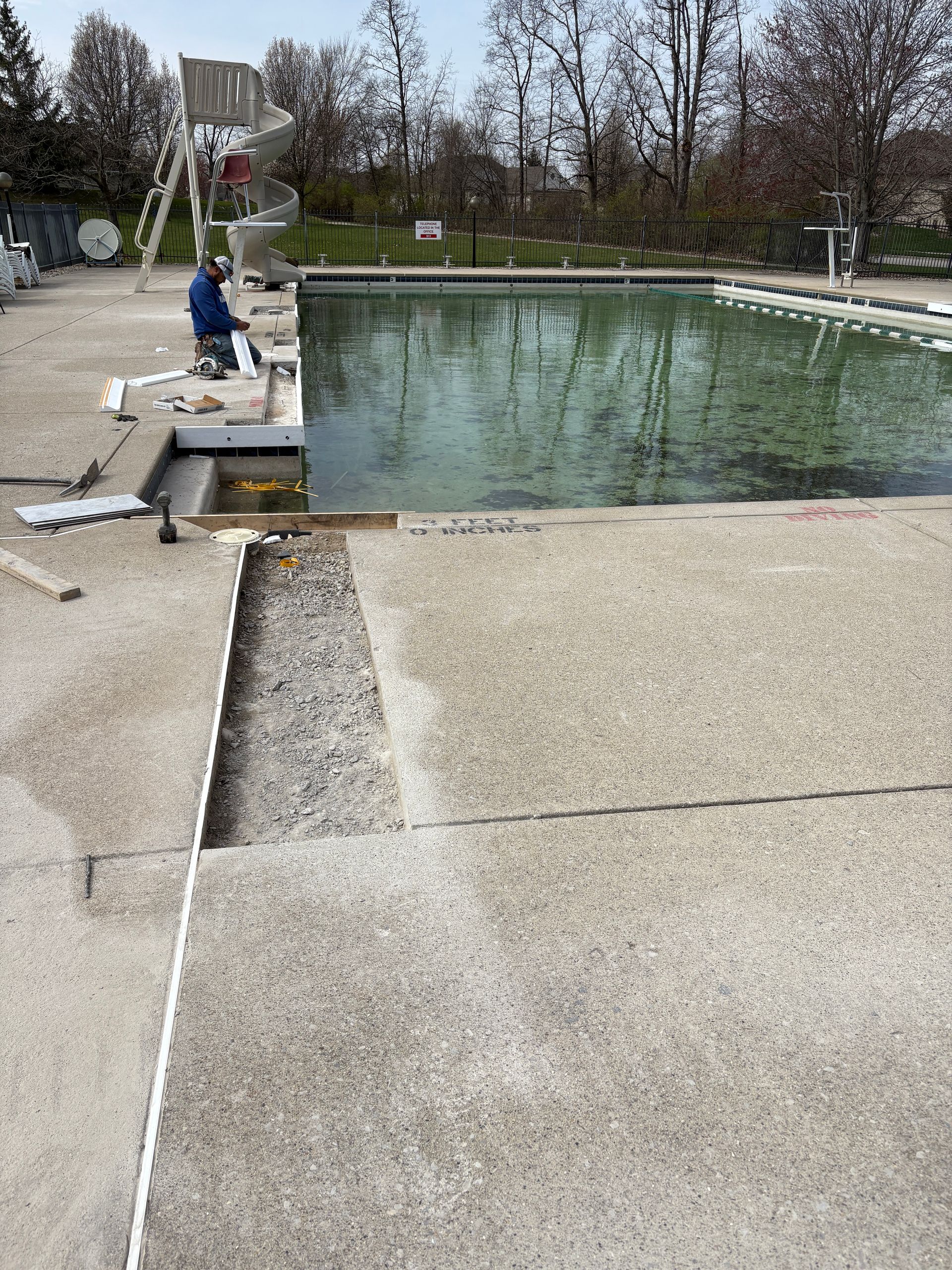 A man is working on the side of a swimming pool