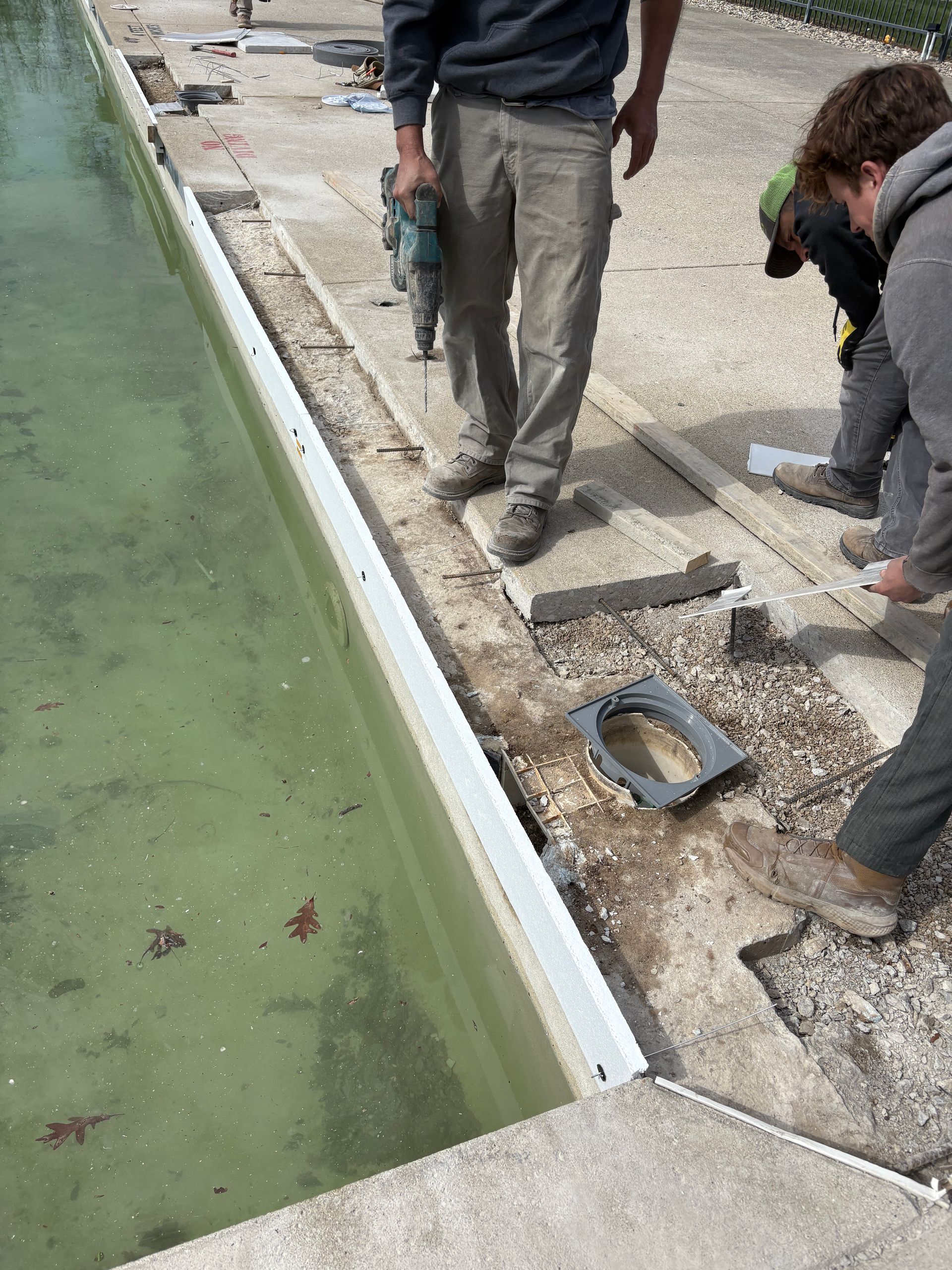 Two men are working on the side of a pool