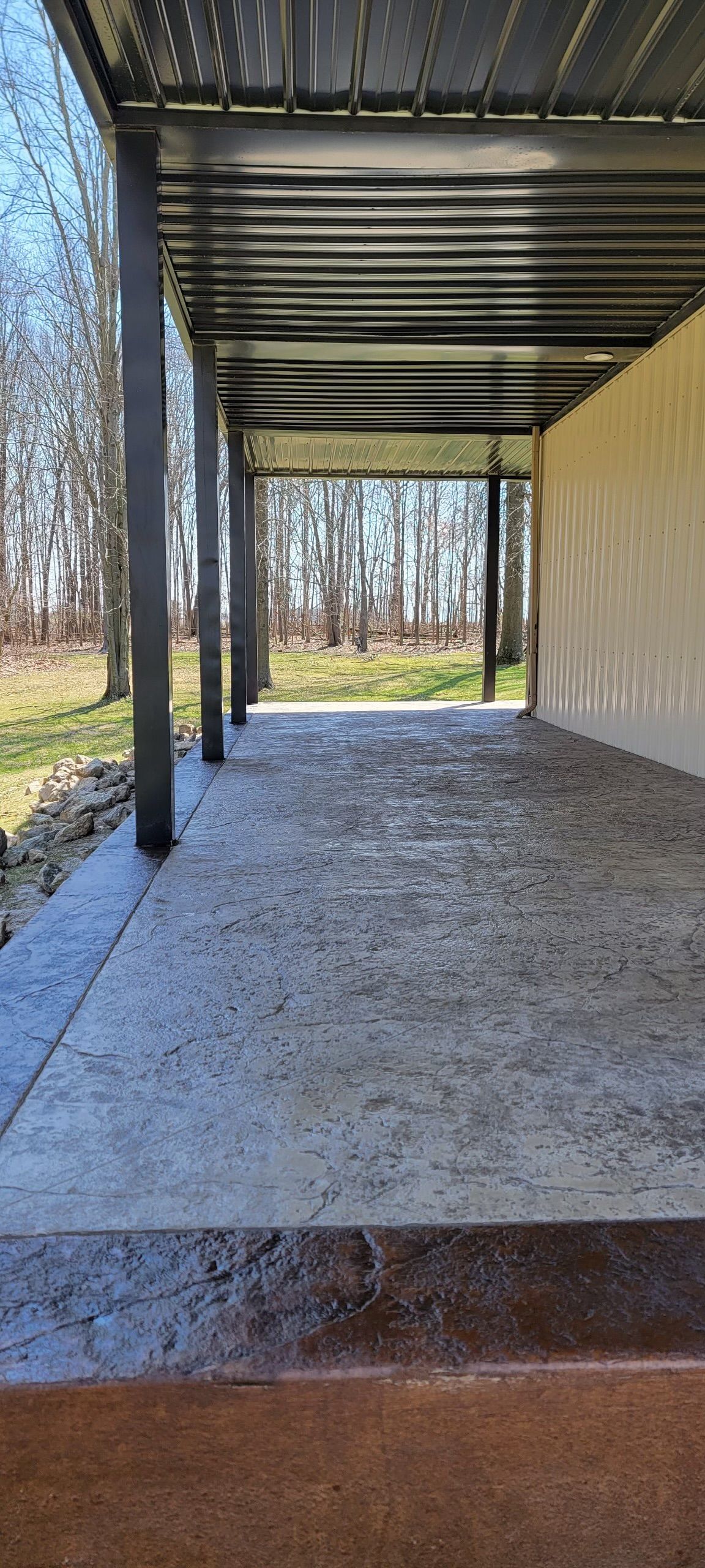 A carport with a concrete floor and a metal roof