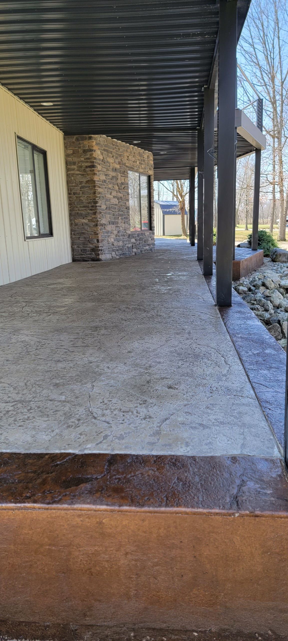 A long concrete walkway leads to a house with a covered porch