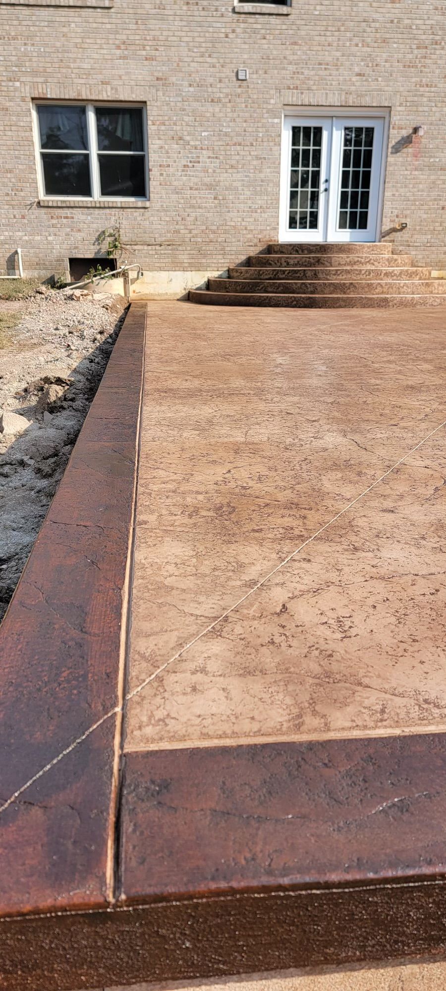 A concrete patio with stairs and a brick building in the background