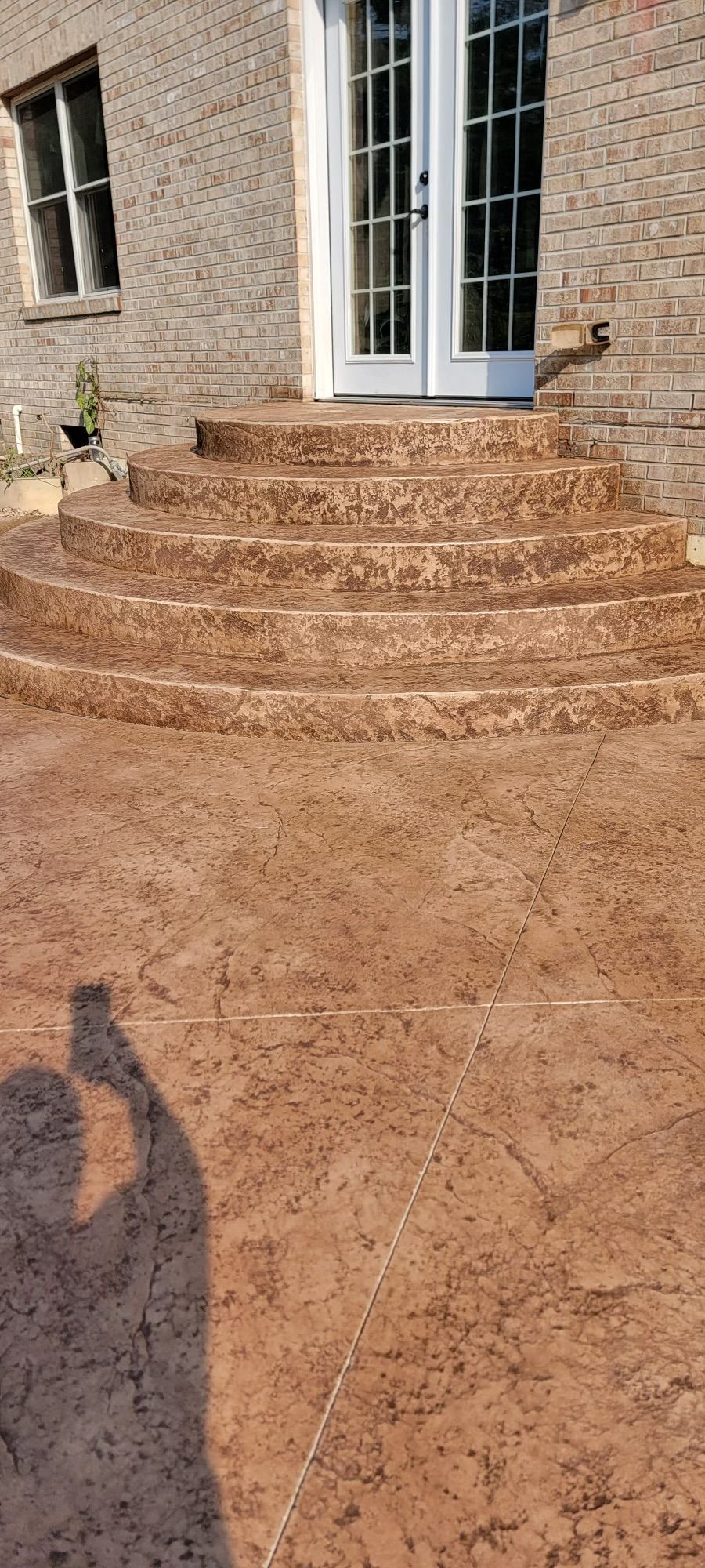 A brown concrete patio with stairs leading up to a brick building
