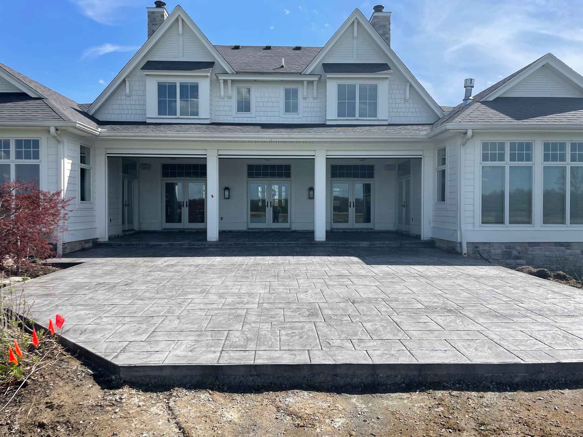 Front view of a white house with a large paved driveway and covered porch.