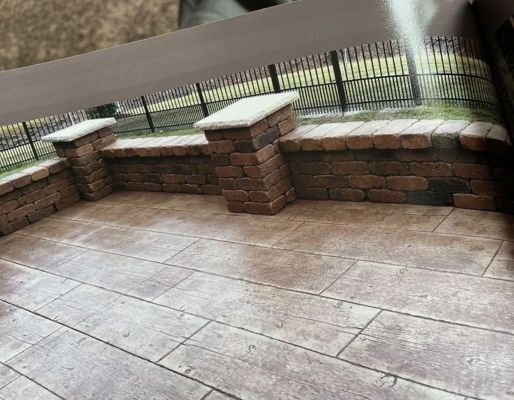 A patio with a brick wall and a fence in the background