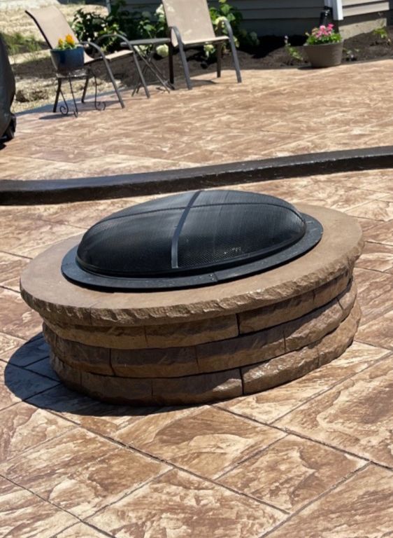 A fire pit is sitting on top of a tiled patio