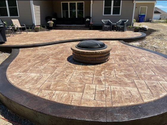 A patio with a fire pit with a cover in the middle of it
