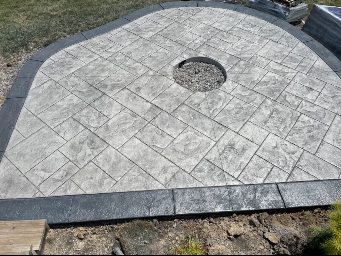 A gray concrete patio with a fire pit in the middle