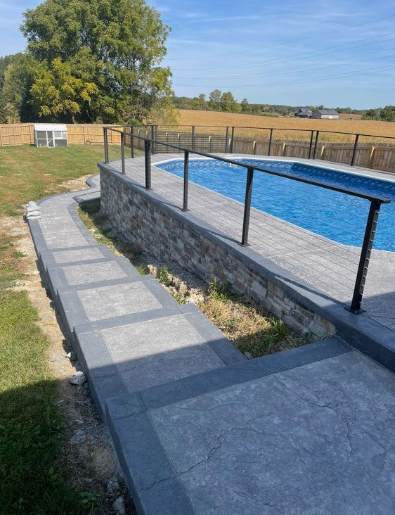 There is a swimming pool in the backyard with a walkway leading to it
