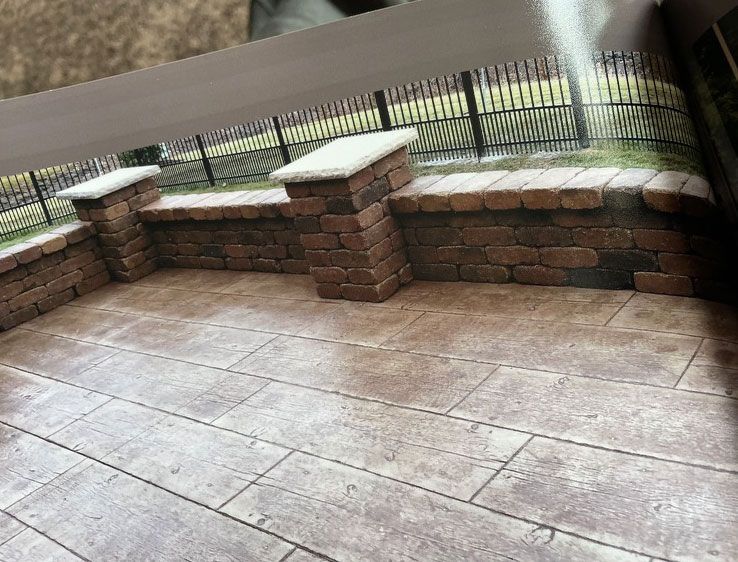 A patio with a brick wall and a fence in the background