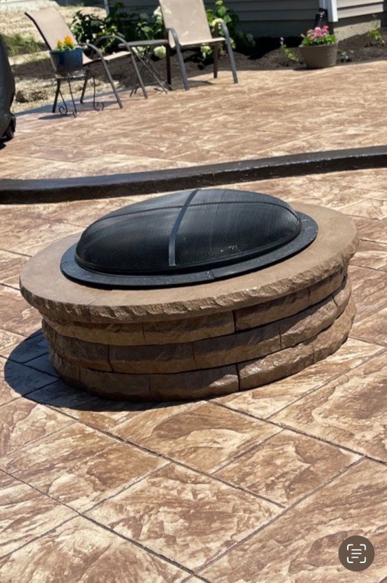 A fire pit is sitting on top of a tiled patio