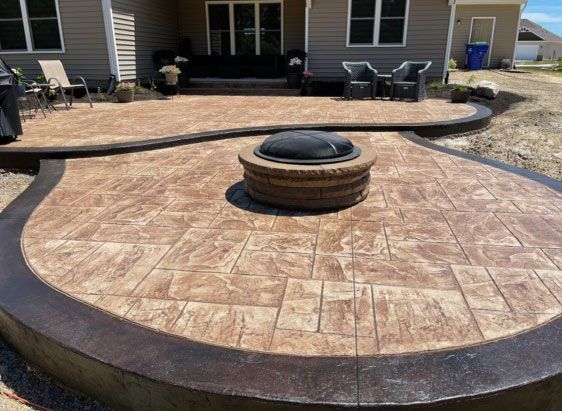 A patio with a fire pit with a cover in the middle of it
