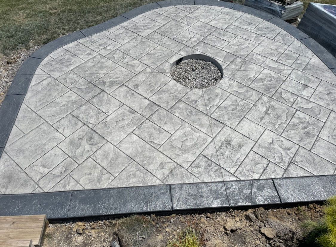 A gray concrete patio with a fire pit in the middle