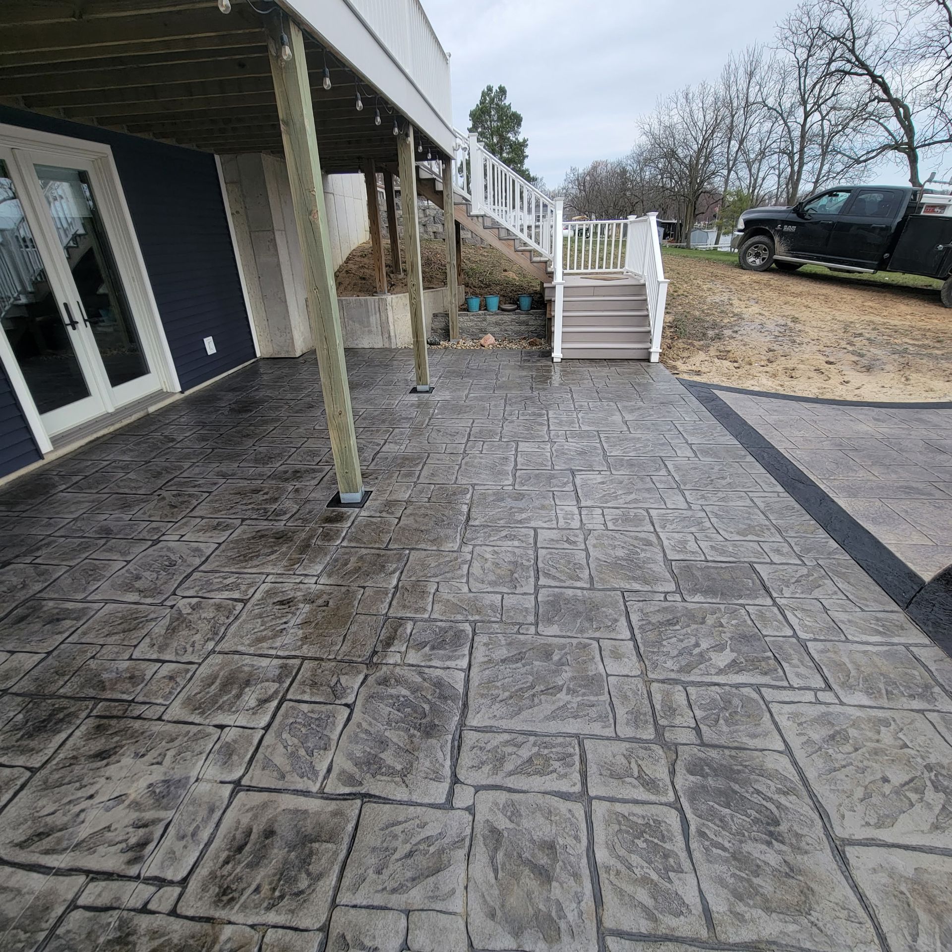 A patio with a deck and stairs underneath it