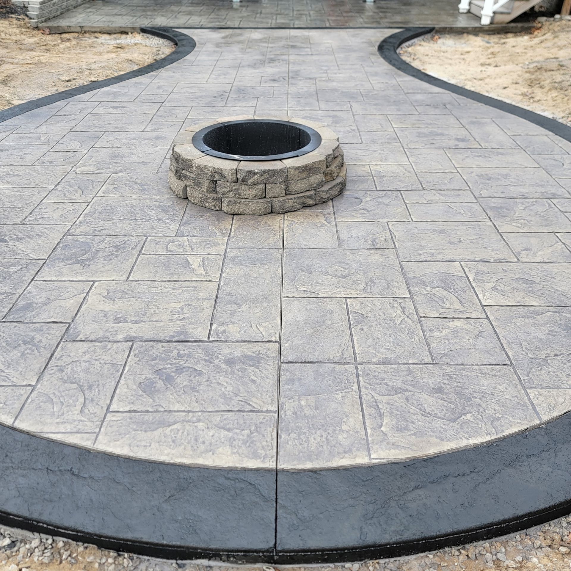 A concrete patio with a fire pit in the middle