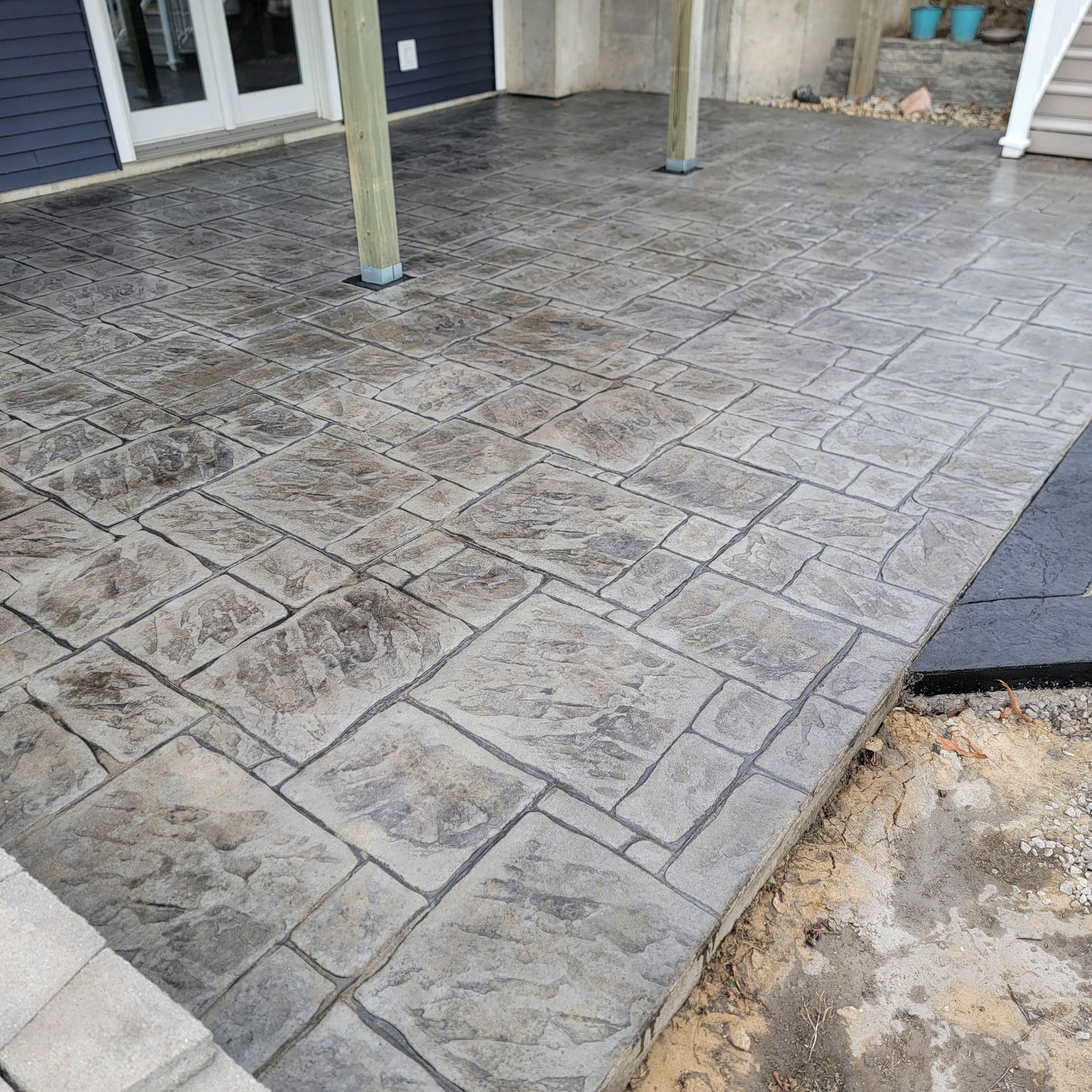 A patio with a gray concrete floor and a blue house in the background