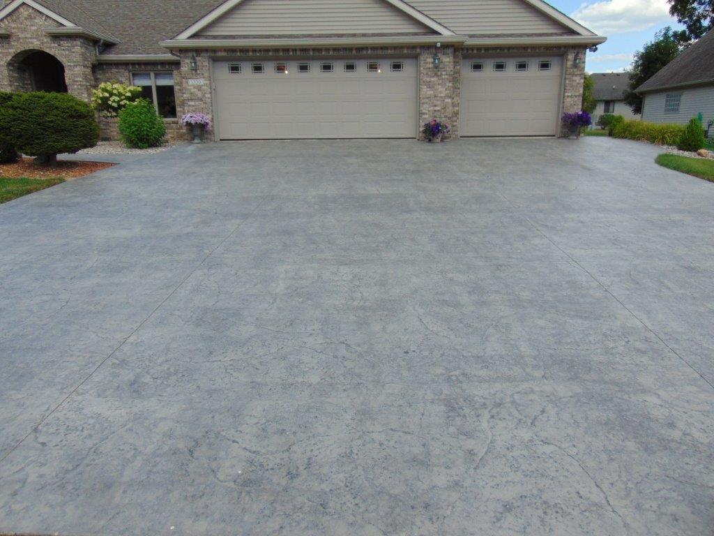 Driveway in front of a house, with two garage doors. The concrete is gray.