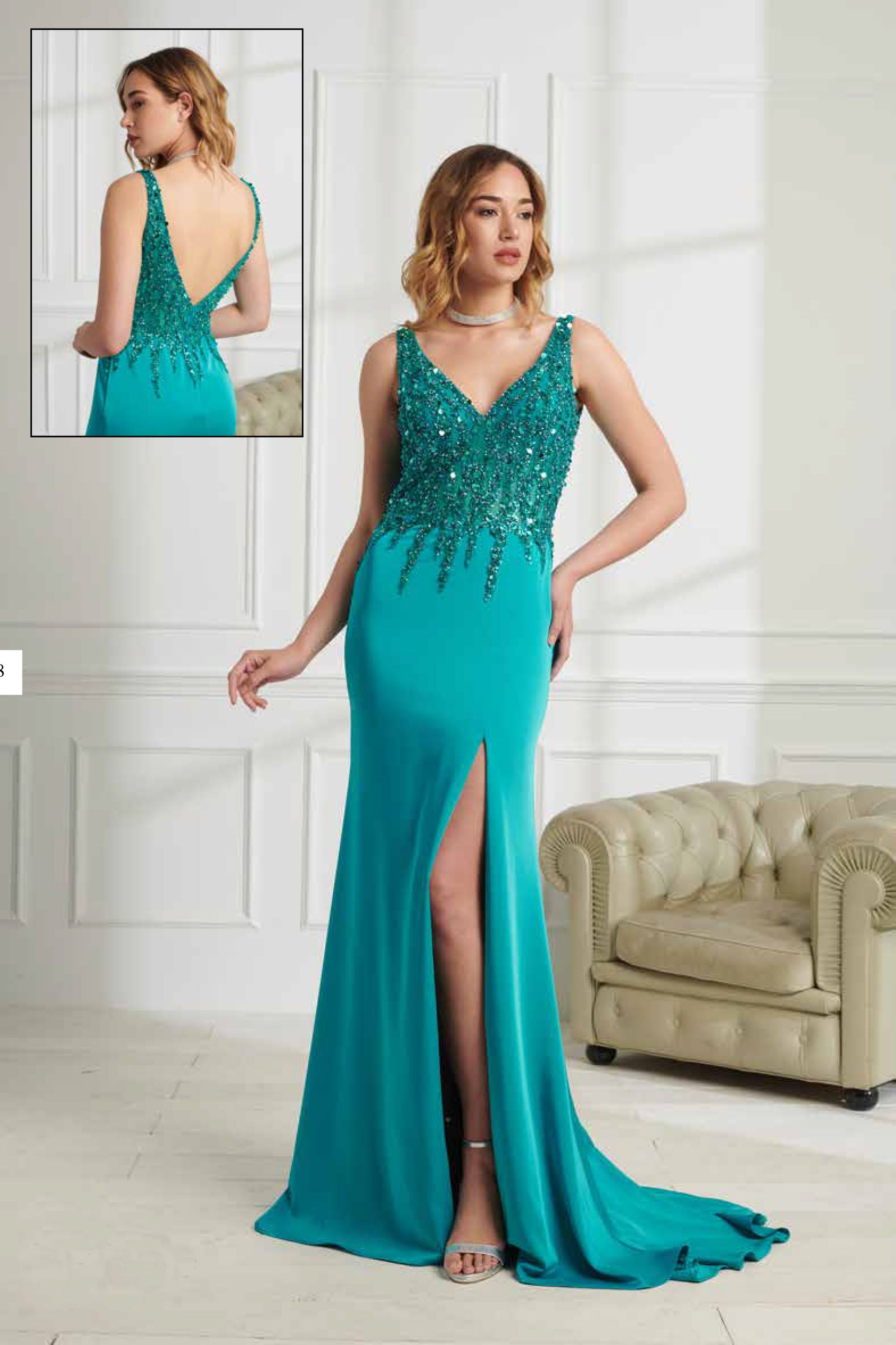 Una donna con un vestito turchese è in piedi davanti a un divano.