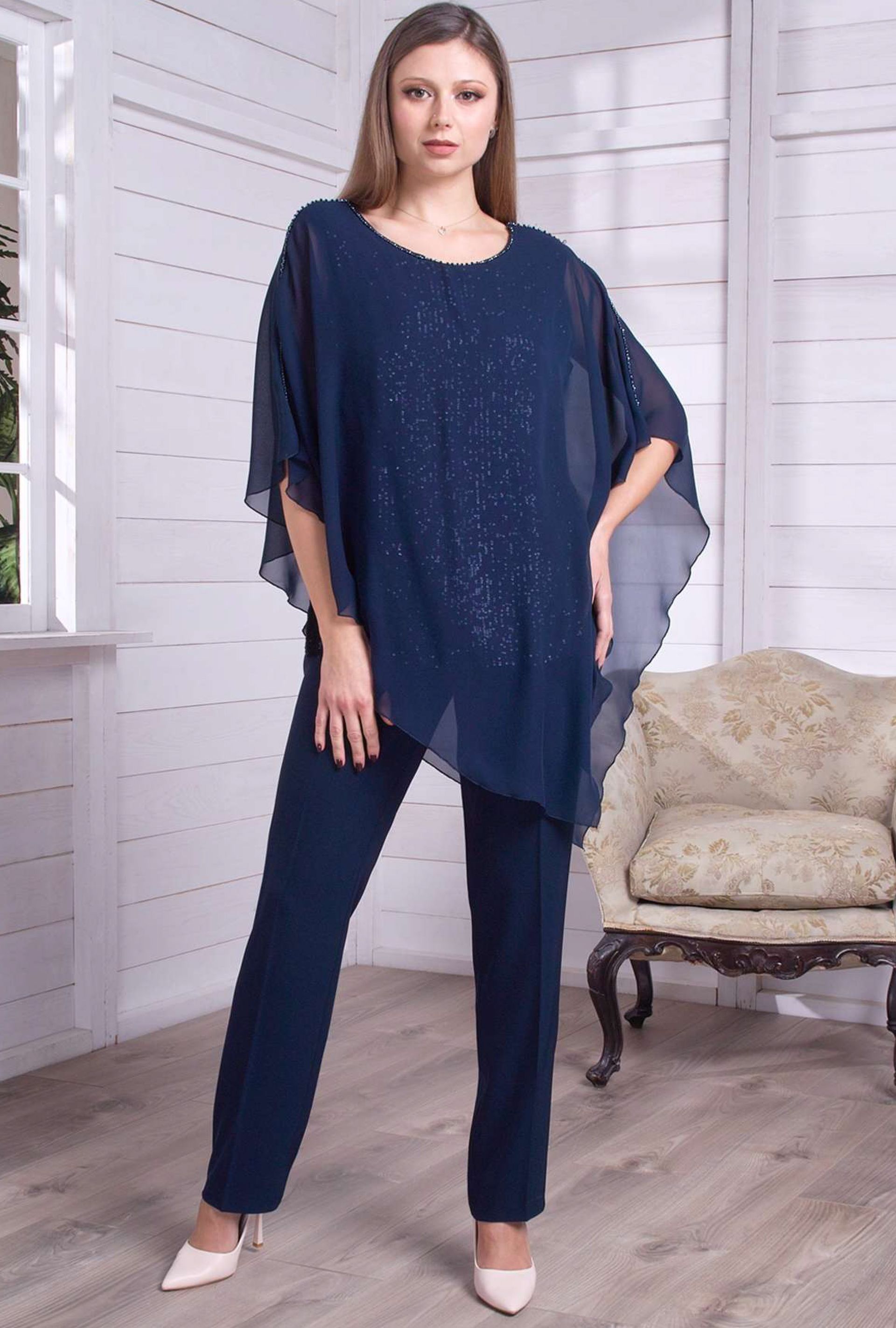 Una donna è in piedi in una stanza e indossa una maglietta blu e dei pantaloni.